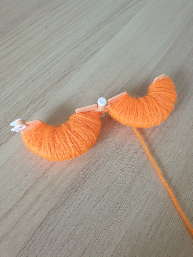 how to create your own halloween pompom bunting showing the pompom maker.