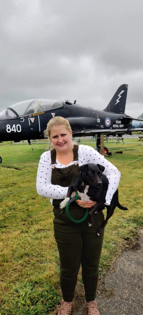 Kelly and Trixie the black dog stood in front of a black hawk aircraft.