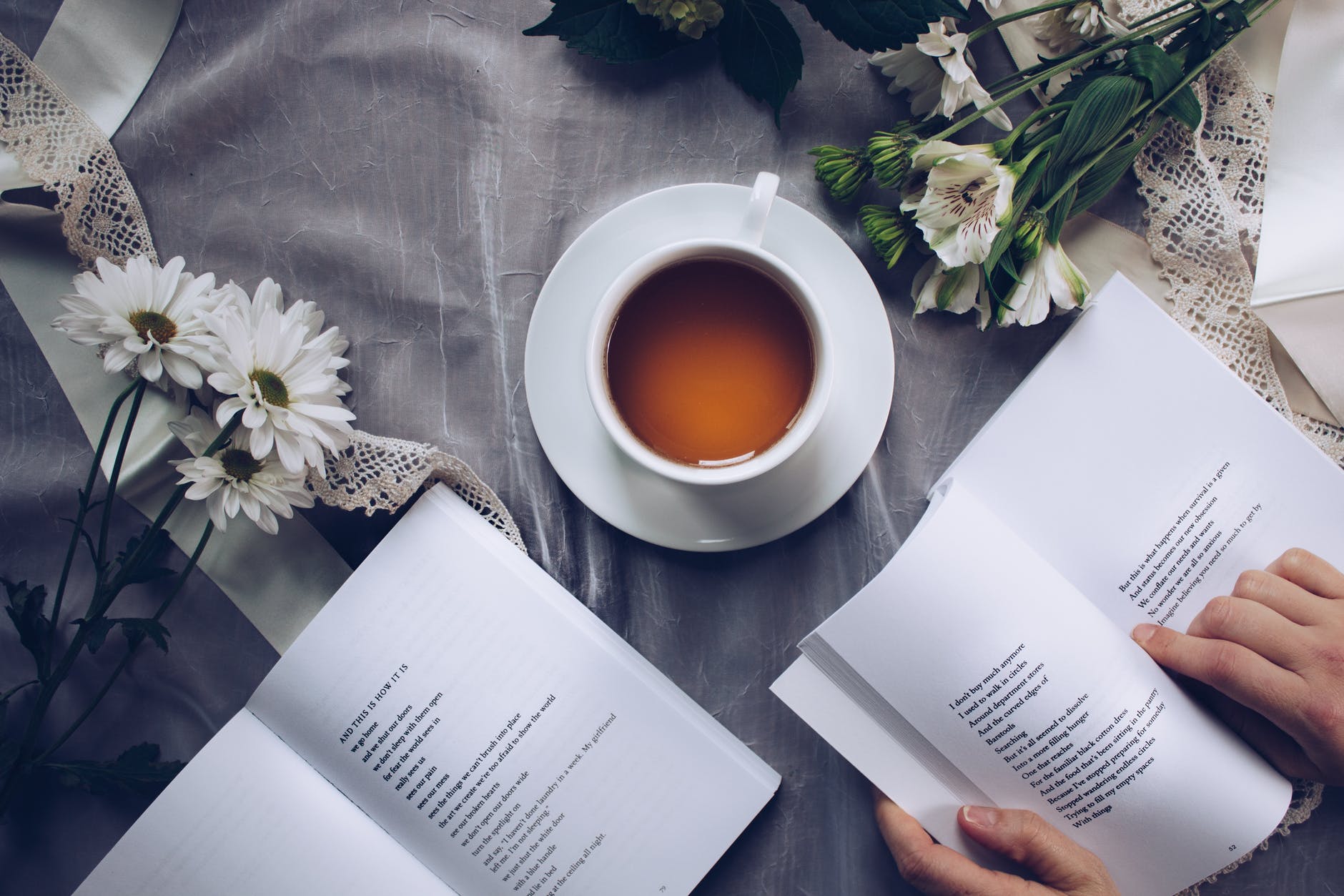 white ceramic teacup with saucer near two books above gray floral textile for The September Girls By Maureen Lee