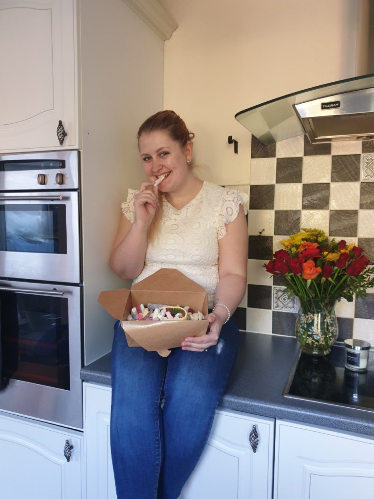 Blonde female sat on kitchen worktop, eating sweets from Panda Sweets pick n mix