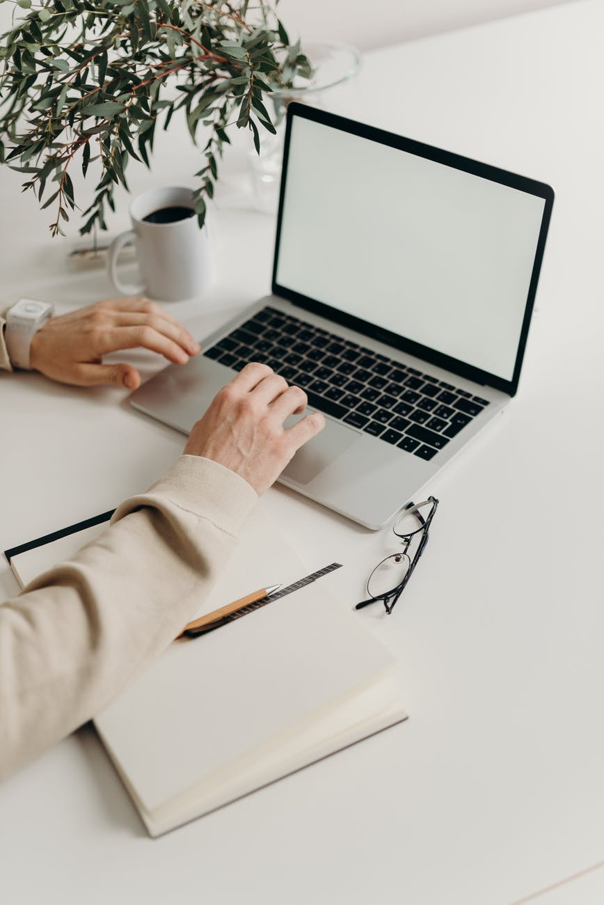 person using macbook pro on white table