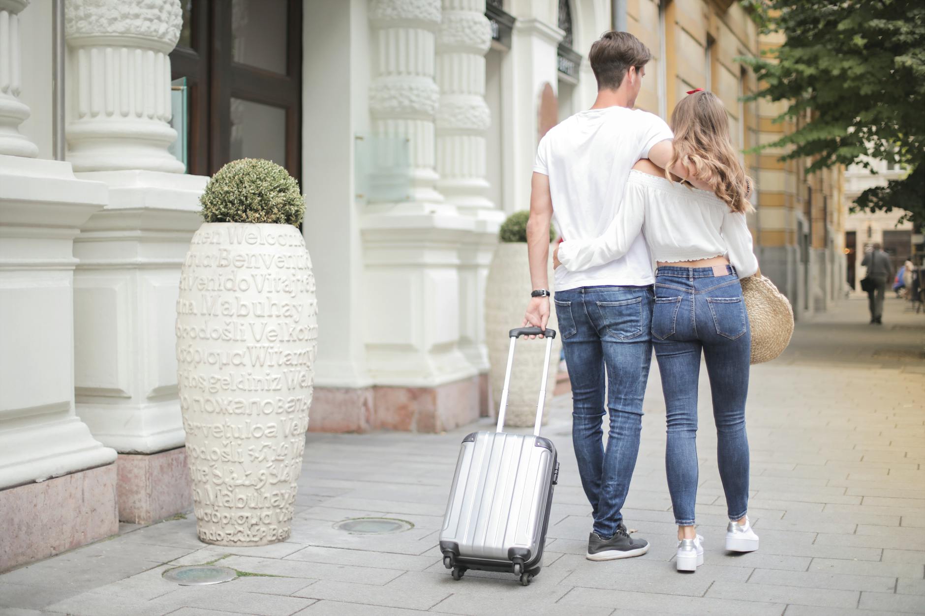 Couple cuddling and walking with a suitcase for best holiday destinations in Europe for couples post.