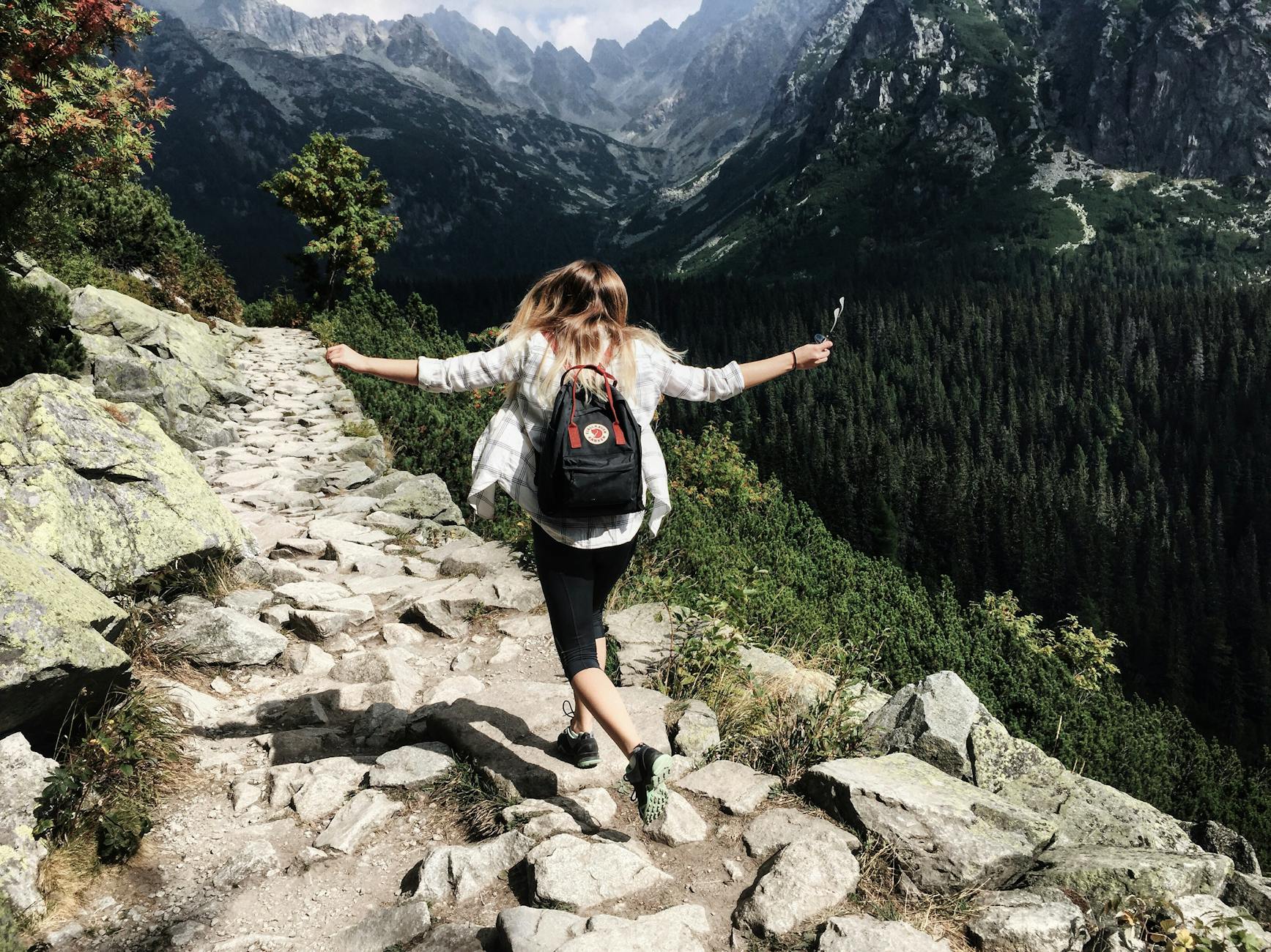 Woman hiking through the mountains for establishing healthy routines for well-being post.