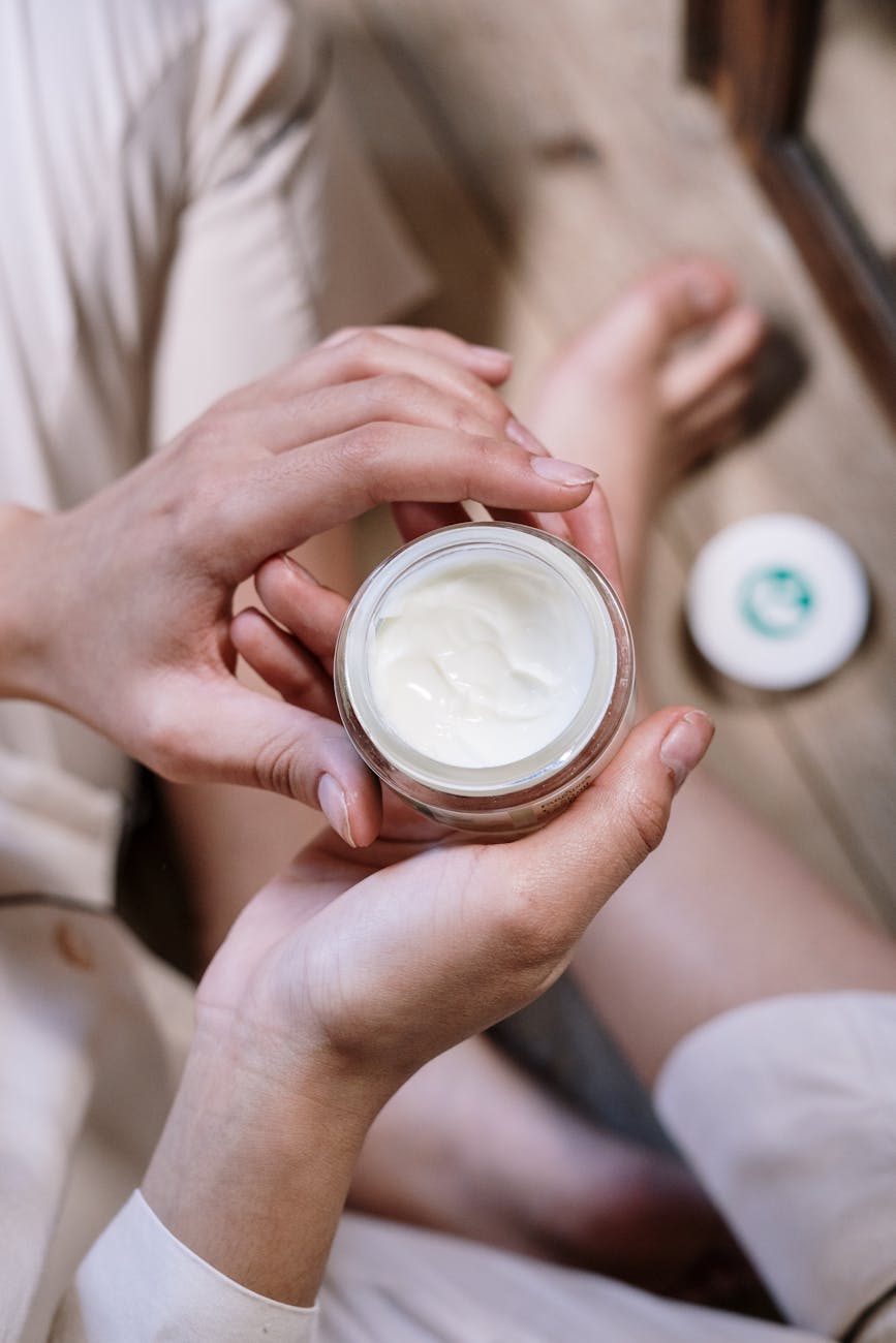 Person holding a round pot of moisturiser for Fall Skincare Switch: Best Routine Changes for Glowing Skin in Cooler Weather post.