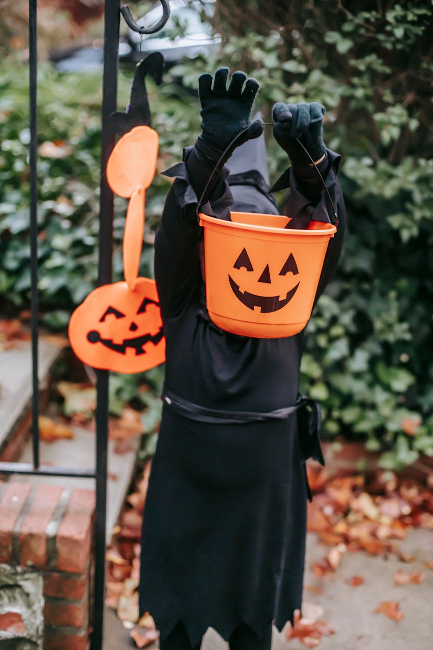 Child holding up a Halloween bucket for How to Plan the Perfect Halloween Scavenger Hunt for Toddlers post.