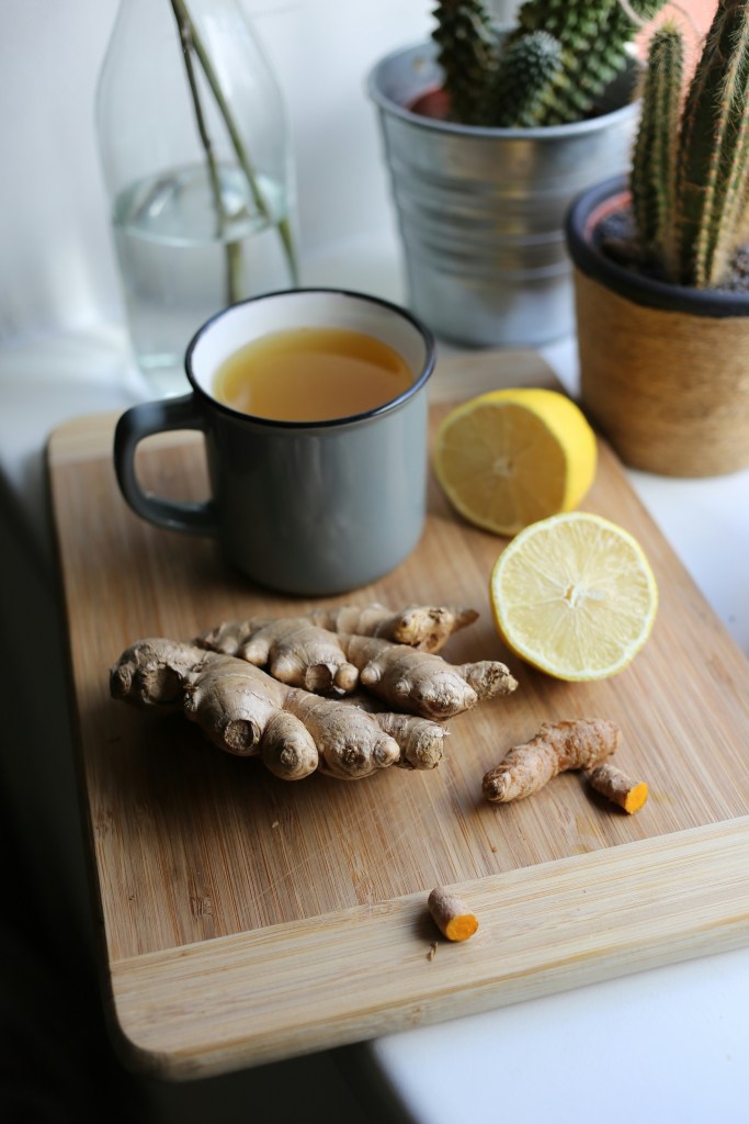 Mug with liquid in, sat on a chopping board alongside ginger and lemon for 6 Everyday Ways to Strengthen Your Immune System Naturally This Winter post.