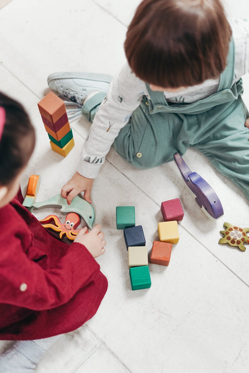 Two toddlers playing with wooden blocks for The Best Baby & Toddler Gifts Age-by-Age: Meaningful Christmas & Birthday Ideas post.