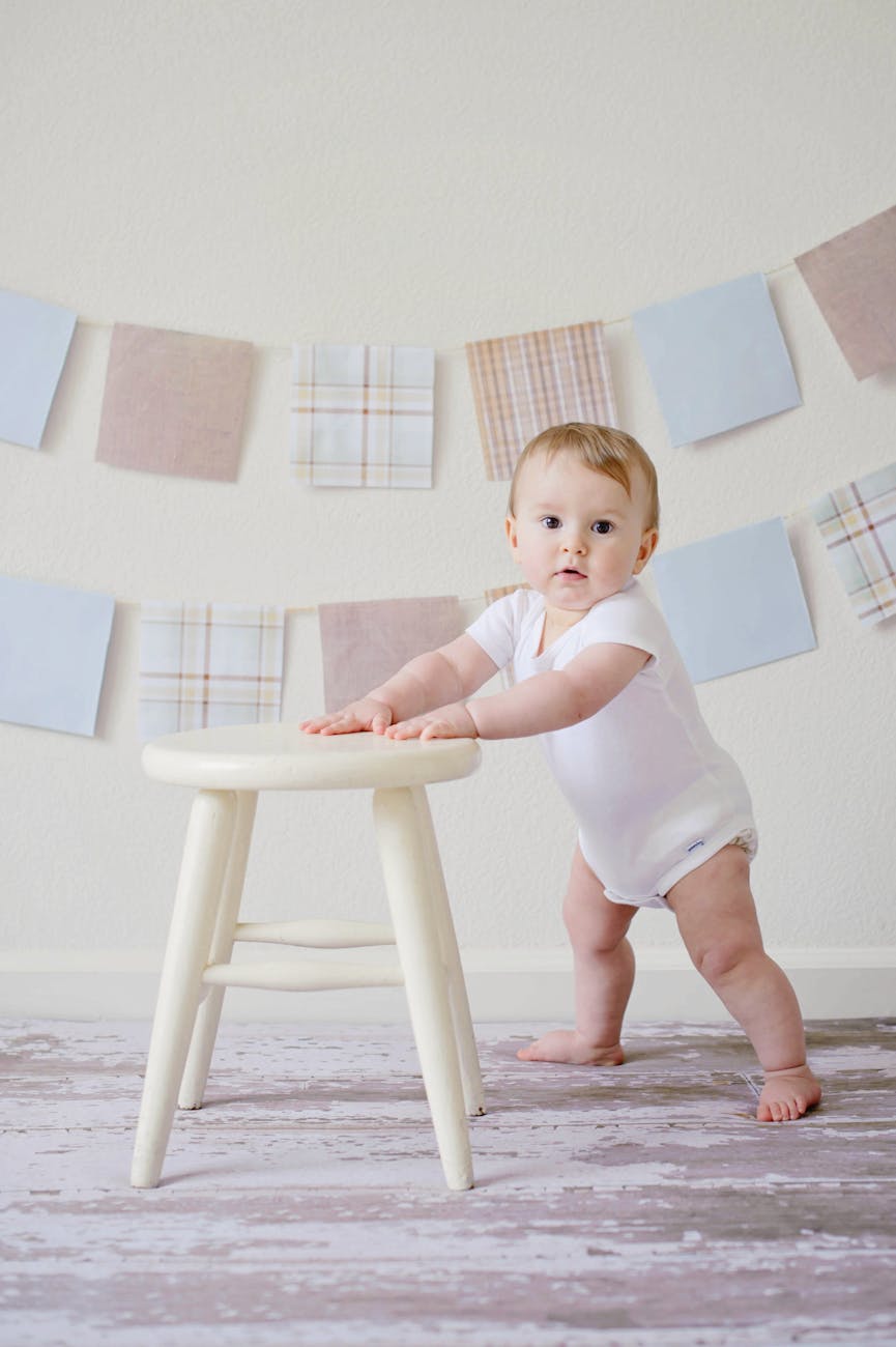 Baby stood holding onto a stool for The Best Baby & Toddler Gifts Age-by-Age: Meaningful Christmas & Birthday Ideas post.
