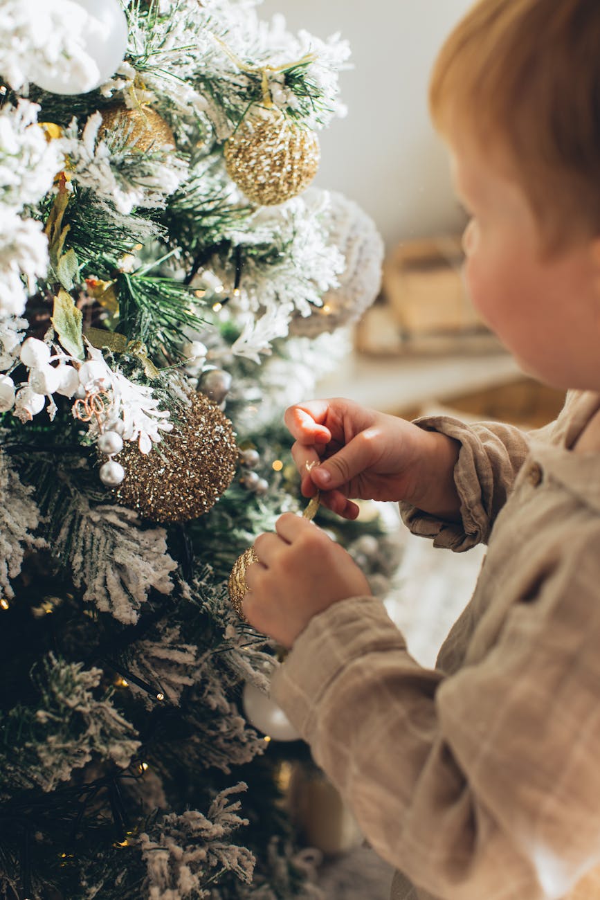 Toddler hanging a decoration on the Christmas tree for 14 Toddler-Friendly Christmas Traditions to Start This Year (Simple, Meaningful & Magical) post.