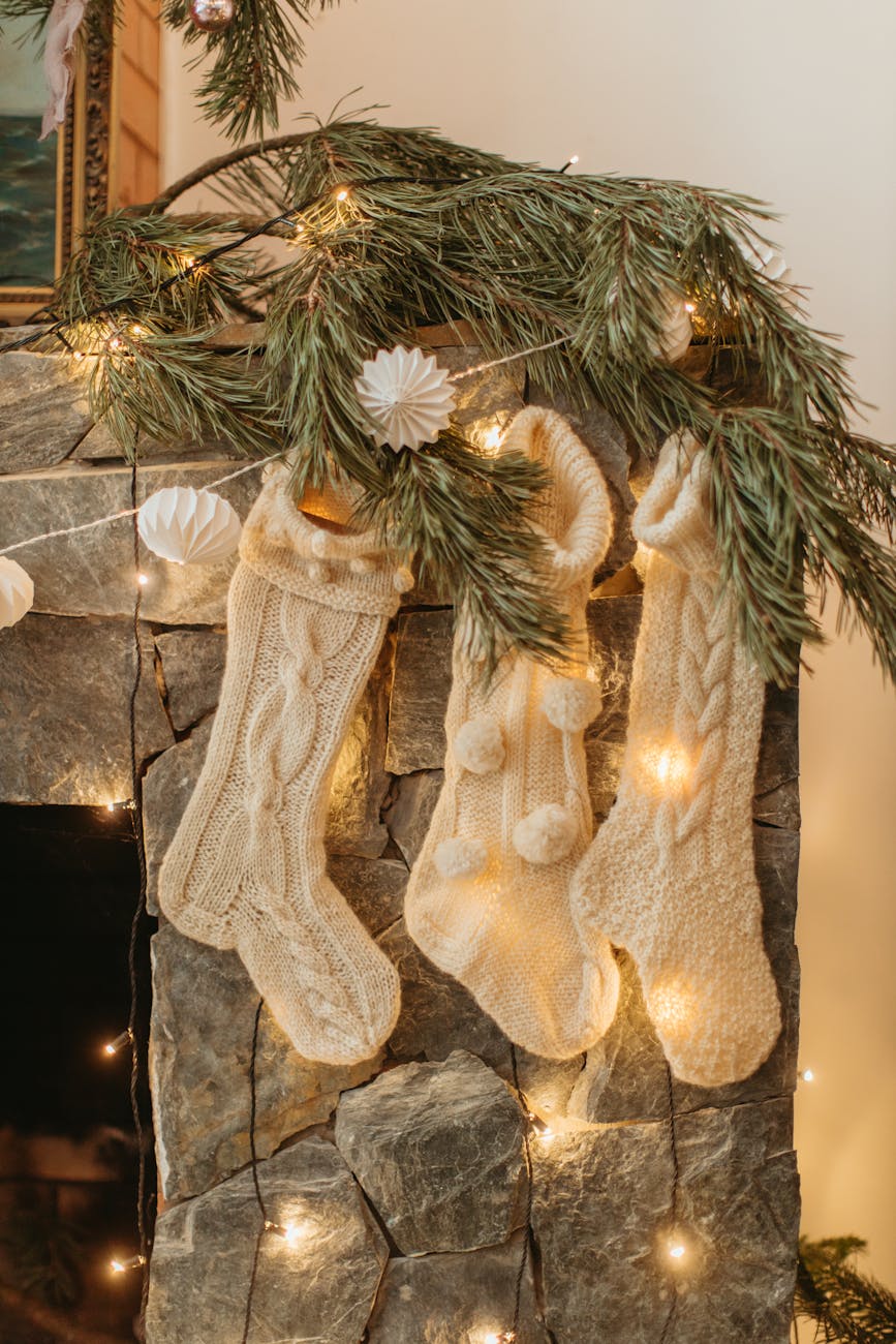 Cream knitted stockings hung from a stone fireplace for The Best Stocking Fillers for Men & Women: Affordable, Thoughtful & Fun Gift Ideas post.