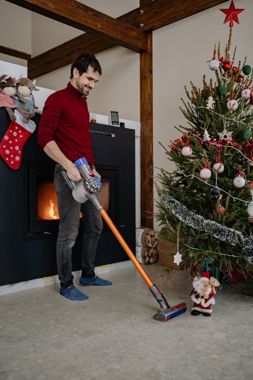 man vacuuming under the Christmas tree for Last-Minute Christmas Cleaning Hacks: Quick & Stress-Free Home Tips post