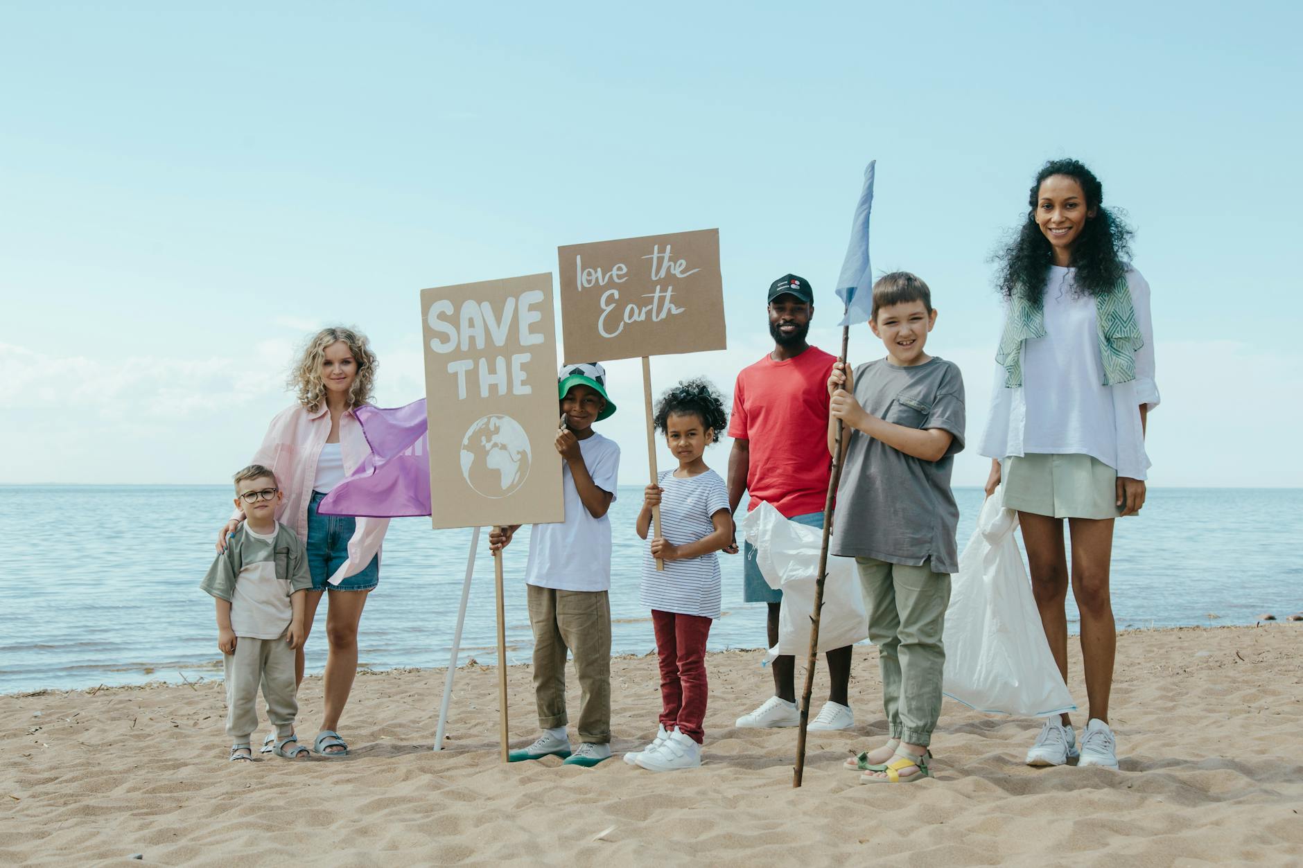 A group of people stood on the beach holding signs that say save our earth for Eco-Friendly Swaps That Are Worth It (And Ones That Aren’t) post.