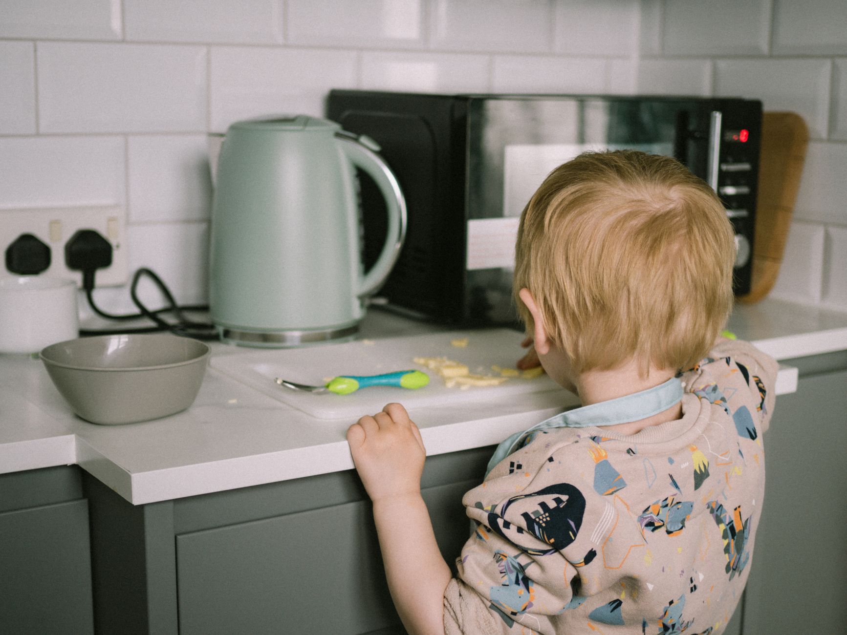 Toddler stood at a kitchen worktop for A Realistic Daily Routine With a Toddler (That Actually Works) post.