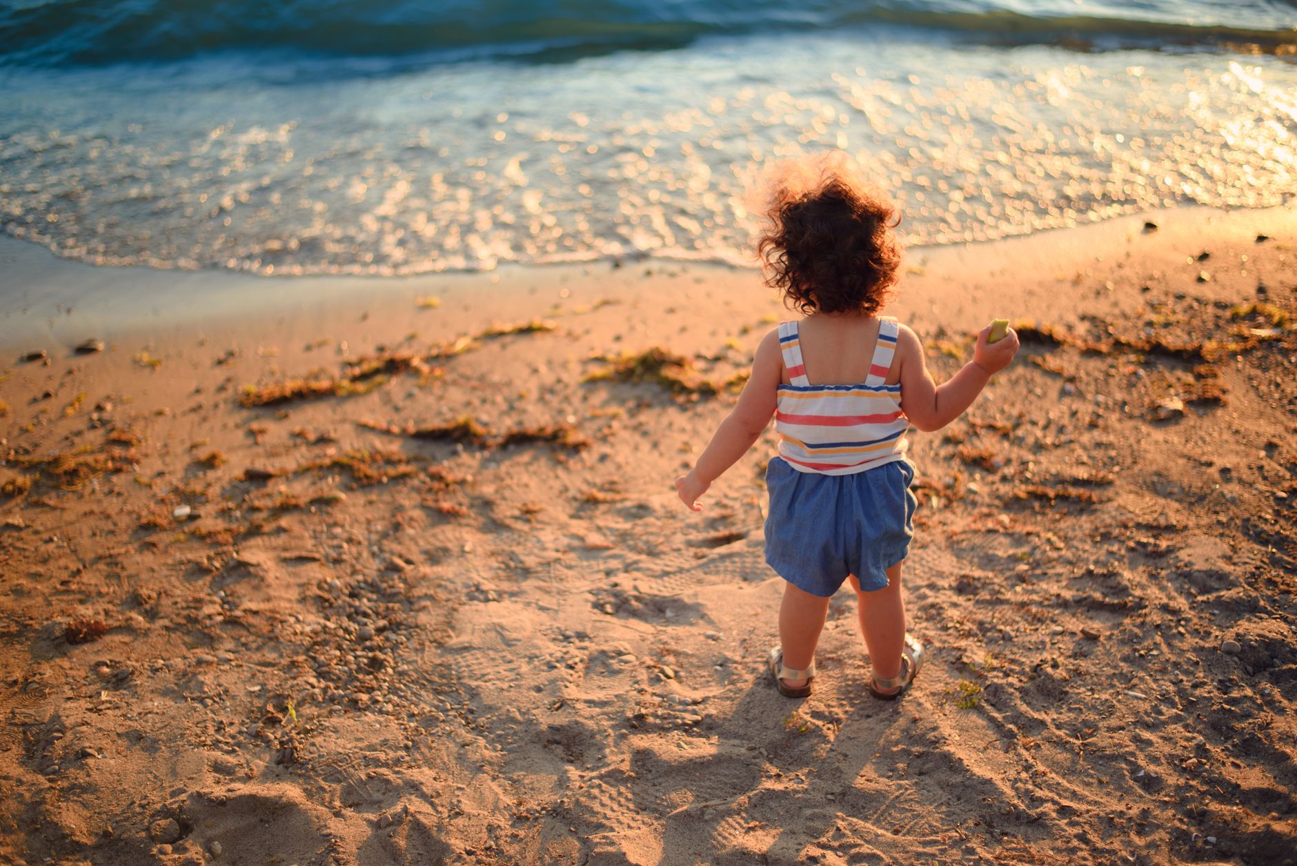 Toddler on a beach looing towards the sea for Best UK Beach Days Out With a Toddler (That Actually Works) post.