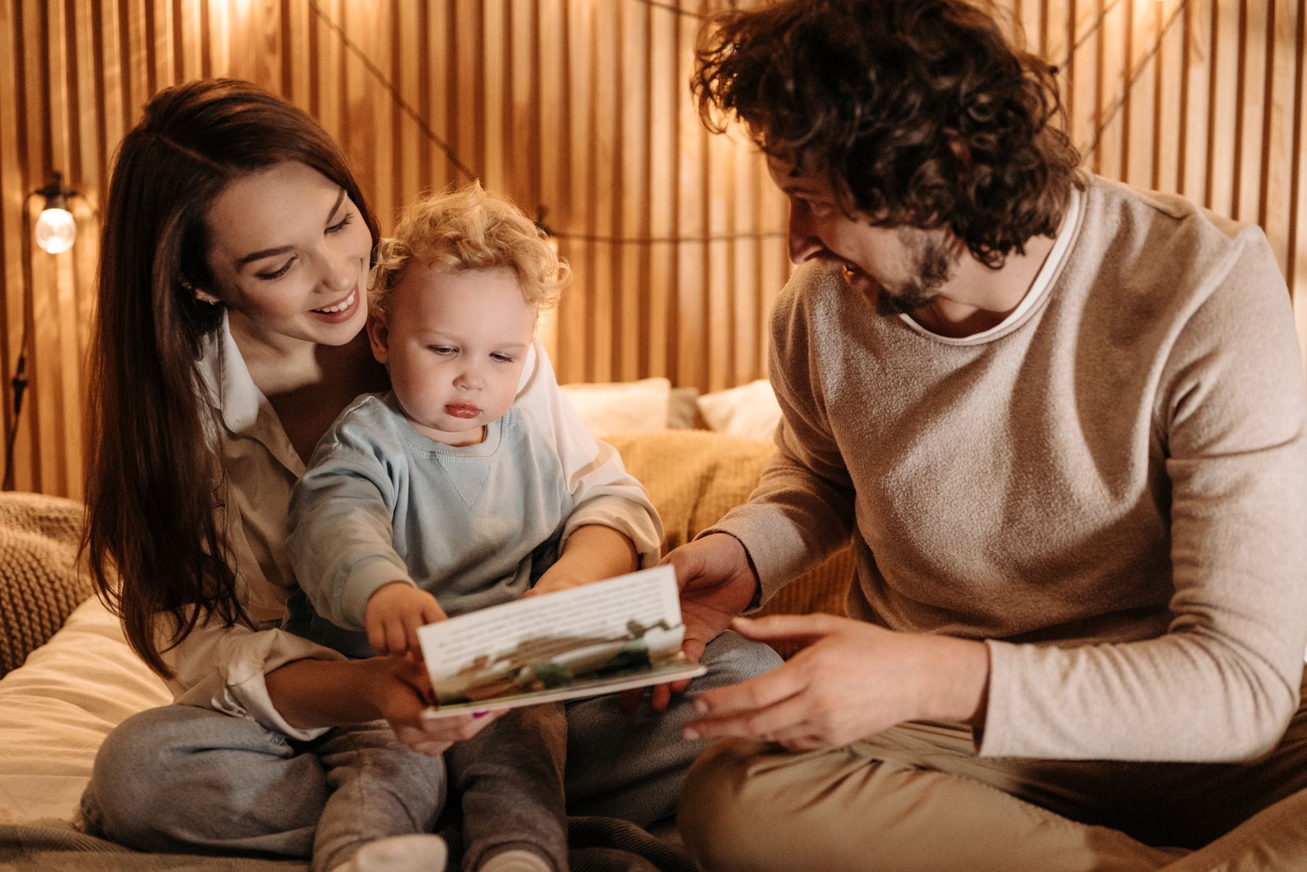 Parents and toddler looking at a book for A Realistic Daily Routine With a Toddler (That Actually Works) post.