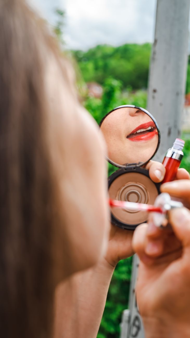 women showing lips and lipstick in a mirror forLow Maintenance Beauty Tips for Busy Mums: How to Look Put Together Without Spending Hours Getting Ready post.