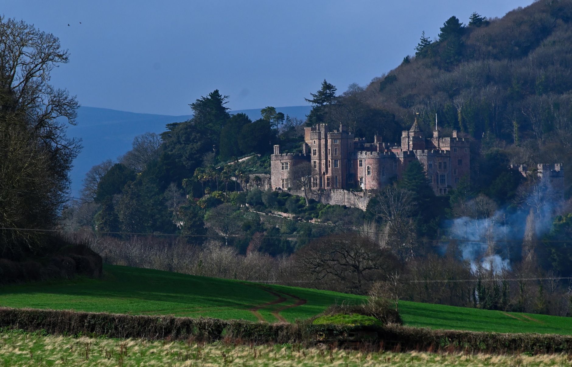 a view of fields in front of Dunster Castle for 20 Cheap Family Days Out in Somerset (That Are Actually Worth It) post.