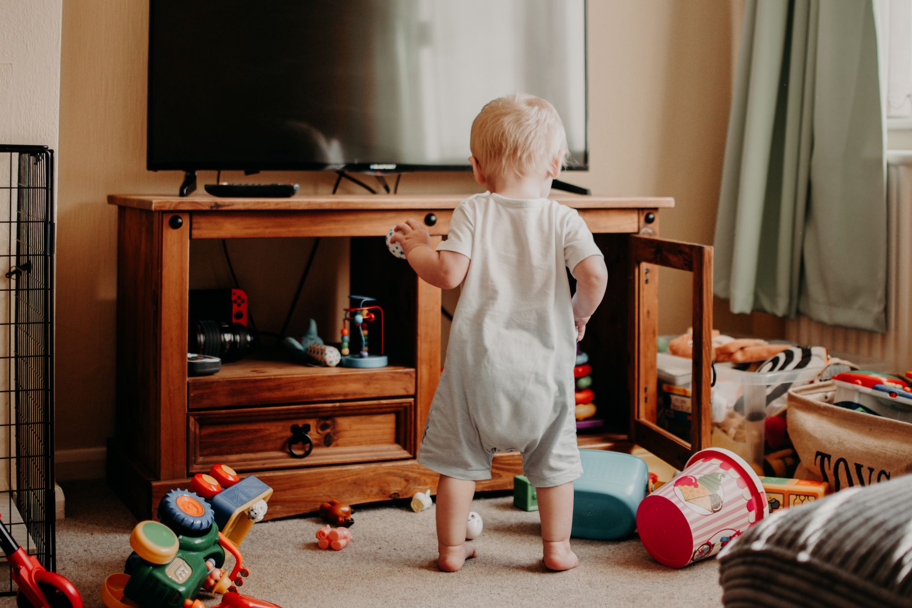 Photo of a living room with toddler and toys everywhere for Things No One Tells You About Parenting Toddlers post.