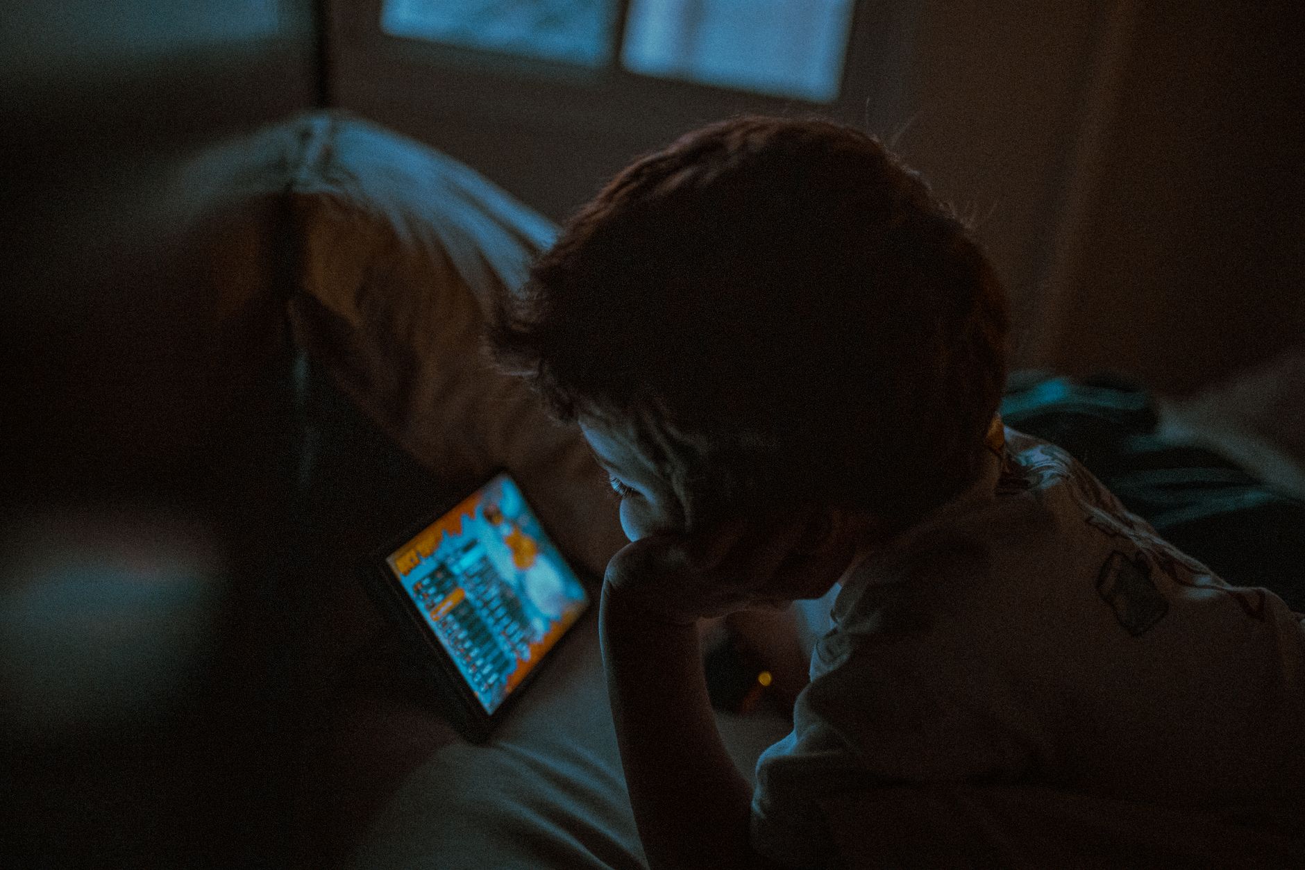 Child watching a screen on a tablet for Managing Screen Time in Winter: Realistic Ideas for the Whole Family post.